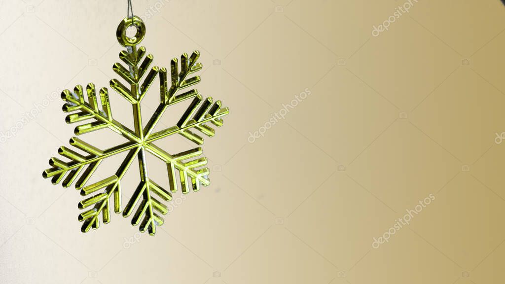 One golden plastic snowflake decoration on a golden background.