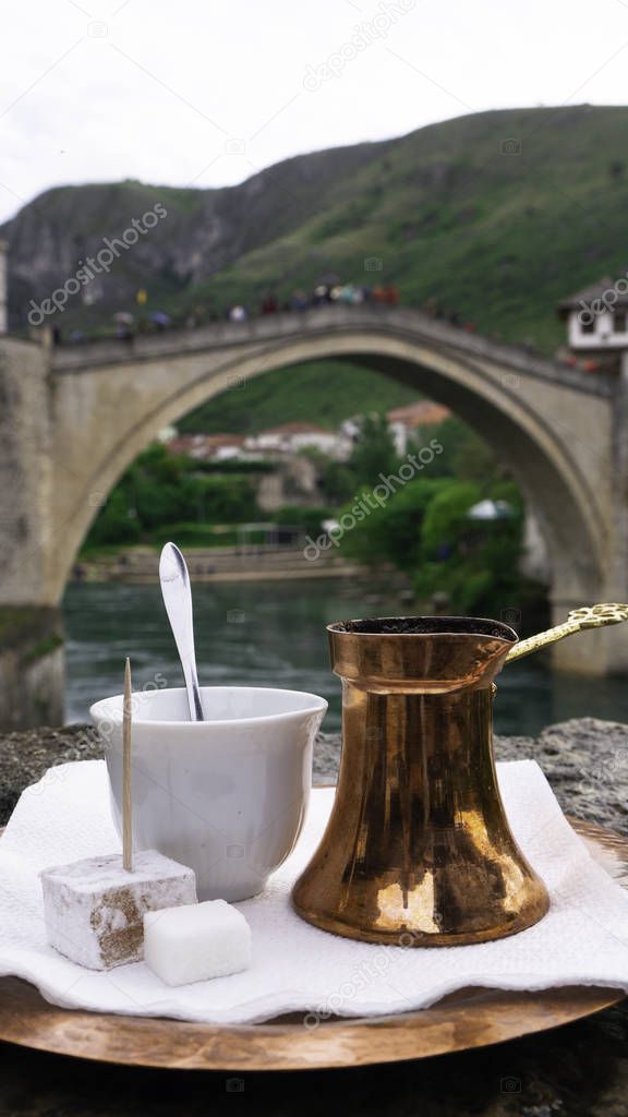 Bosnian coffee with delight and traditional copper serving set  in front of Old bridge in Mostar, Bosnia and Herzegovina. 