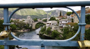 Mostar 'ın manzarası, Neretva nehri üzerindeki bir liman köprüsünün çitinden geçiyor. Mostar, Bosna-Hersek.