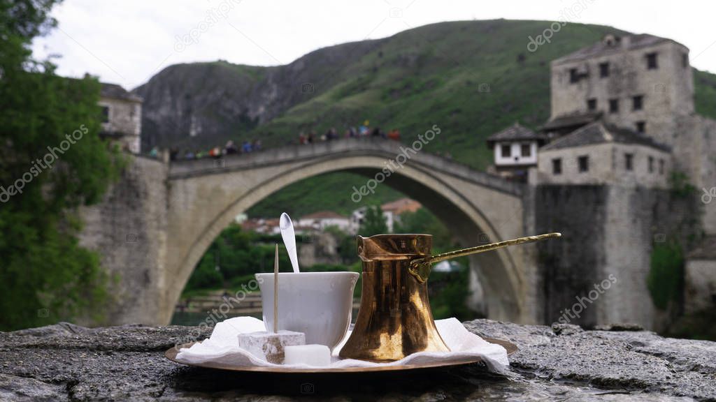 Traditional Turkish coffee and a view of Mostar Old bridge and river Neretva. Bosnian coffee in a cezve with a turkish delight, Mostar, Bosnia And Herzegovina. 