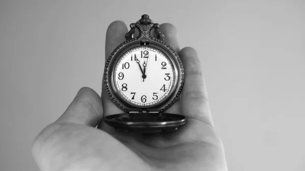 Five minutes to twelve o\'clock. Old pocket watch in young woman\'s hand. Black and white photo.  Copy space for advertising.