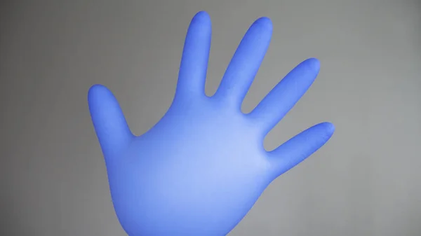 stock image Inflatable blue rubber glove on a gray background.