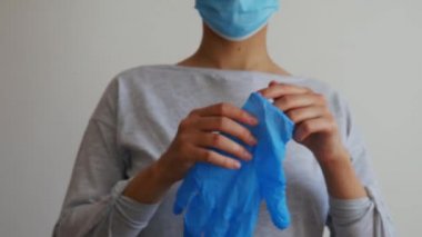 Maskeli kadın doktor veya hemşire lastik eldiven takıyor..