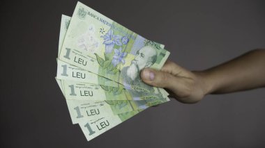 Elinde bir Romen leu banknotunun beş faturası. 