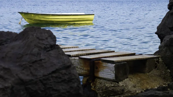 岩石海岸 有木制防波堤 海上有一艘黄色的船 — 图库照片