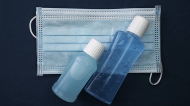 Mavi arka planda bakteri ve virüs için hijyenik yüz maskesi ve Alkol jeli dezenfektan el temizleyicisi..