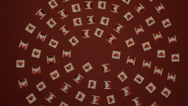 White spiral formed with small squares and red hearts on them spins around and falls apart to leave blank burgundy space for St. Valentine`s greetings — Stock Video