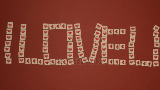 St. Valentine's day stop motion animatie wenskaart met de woorden ik hou van U-vormige door doek kwadraten van witte kleur met rode glanzende harten — Stockvideo