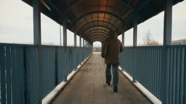 Bej bir palto yaya köprüsü arasında karayolu üzerinde çalışan adamla