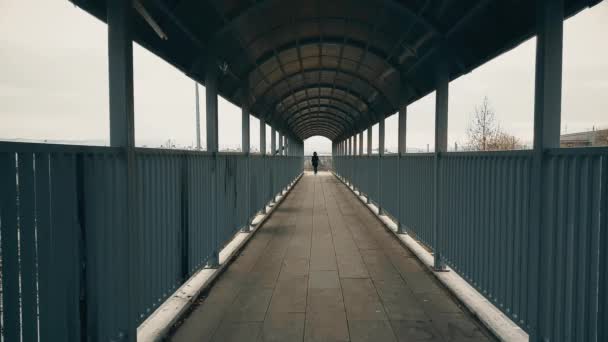 Frau mit schwarzem Mantel läuft über Fußgängerbrücke über Autobahn — Stockvideo