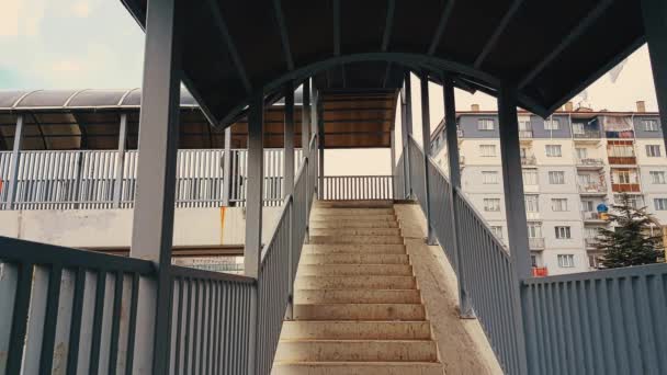 Un hombre con abrigo beige corriendo por las escaleras de la pasarela — Vídeo de stock