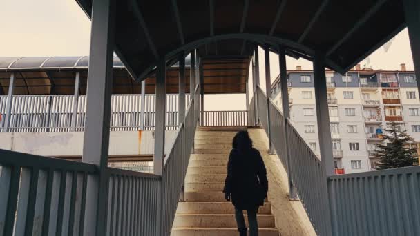 Γυναίκα με μαύρο παλτό ανεβαίνοντας τις σκάλες της γέφυρας — Αρχείο Βίντεο