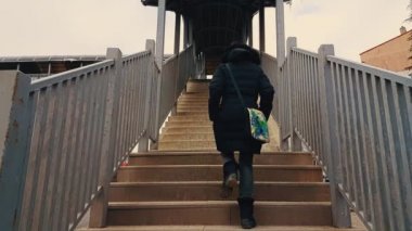 Kadın siyah montlu yaya merdivenlerden yukarı yürümek