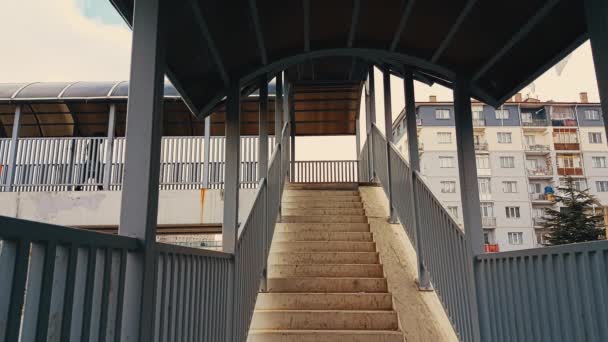 Femme avec manteau noir marchant dans les escaliers de la passerelle — Video