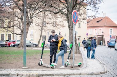 Prag, Çek Cumhuriyeti 3 Mart 2019. Şehir merkezinde cep telefonu uygulaması olan bir motosiklet kiralayan genç bir adam ve kız.
