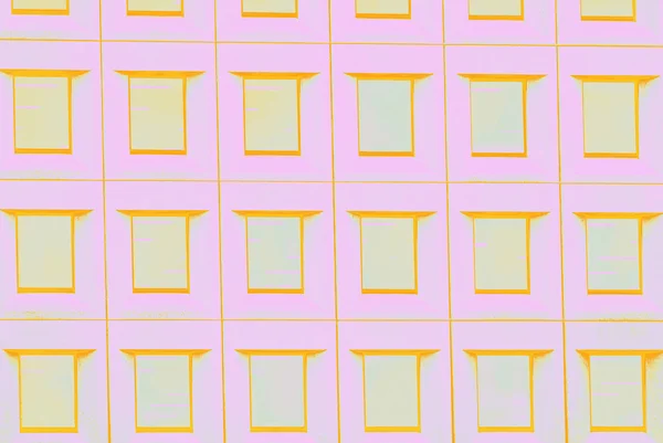 Бледно-розовая стена и желто-оранжевый рисунок окон, фон — стоковое фото
