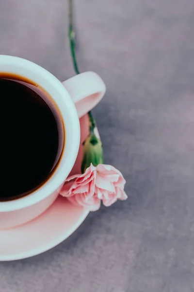Розовый чашка черного кофе и розовый цветок гвоздики на сером бетонном фоне — стоковое фото