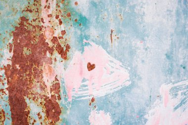 Pembe, yeşil, mavi, turkuaz boyalı paslı metal yüzey. Küçük kalp. Eski çatlak boya deseni, çatlayan doku.