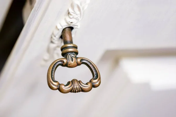 Una llave vieja en el ojo de la cerradura. Llave en puerta de madera blanca —  Fotos de Stock