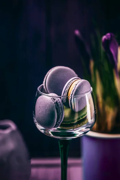 Exquisito francés violeta lavanda macarrones o macarrones en un vaso y azafrán flores sobre fondo oscuro — Foto de Stock