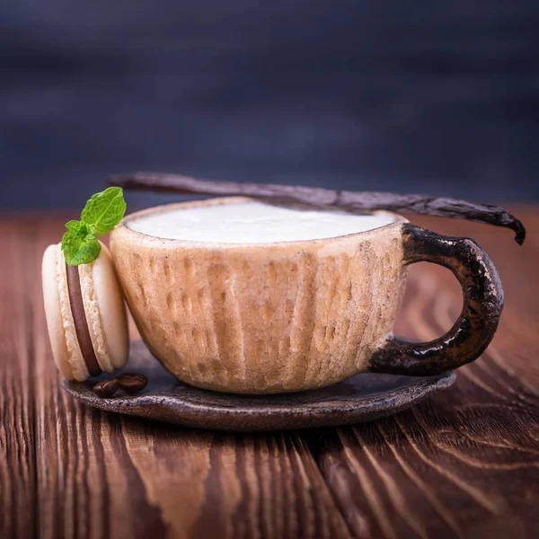 Kaffee-Cappuccino, Vanilleschote und Schokoladenmakronen oder Macaron mit Minzblatt auf dunklem Holzgrund — Stockfoto