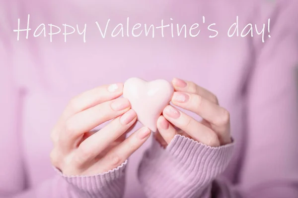 Valentines day greeting card. Beautiful female hands holding pale pink heart on the violet background — Stok fotoğraf