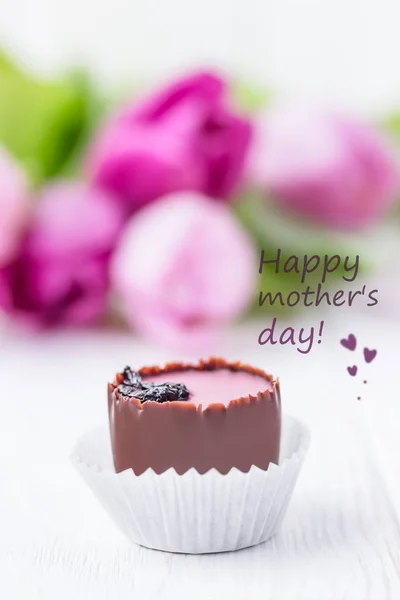 Anneler günün kutlu olsun. Yazı, metin, kelimeler. Beyaz arka planda çikolatalı şeker ve pembe laleler. — Stok fotoğraf