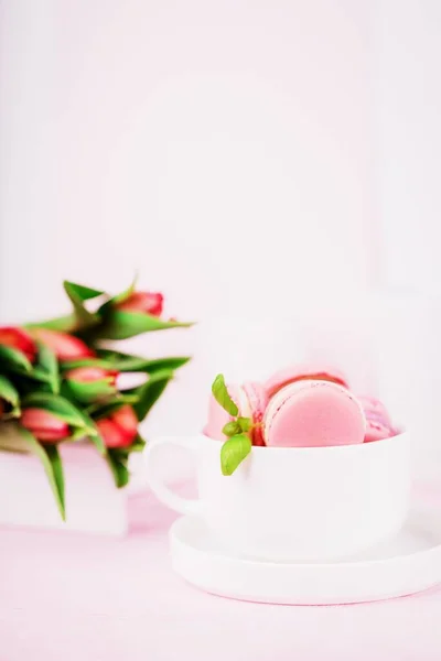 Postre francés casero macarrones rosados o macarrones y tulipanes de primavera sobre fondo rosa, espacio para copiar — Foto de Stock
