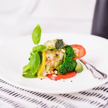 Buğulanmış balık filetosu brokoli, domates, limon, avokado, fesleğen sosu ve çam fıstığı beyaz arka planda kopyala