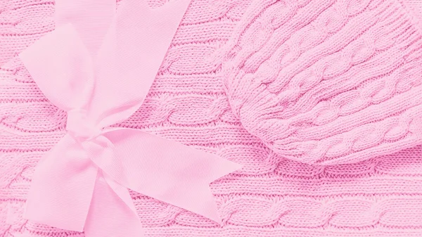 Yumuşak pembe bir battaniyeye bebek şapkası örülmüş. Yayı olan yeni doğmuş bebek için şirin bir hediye. Uzayı kopyala, 9 panoramik formatta 16