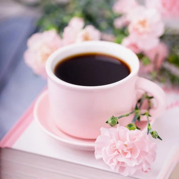 Pembe kahve, kitaplar ve pastel pembe karanfil çiçekleri, dikey fotoğraf.