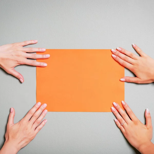 Mãos Femininas Segurando Papel Laranja Branco Folha Papel Fundo Cinza — Fotografia de Stock