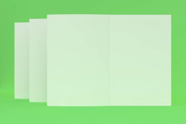 Üç boş beyaz açık broşür mock-up yeşil zemin üzerine