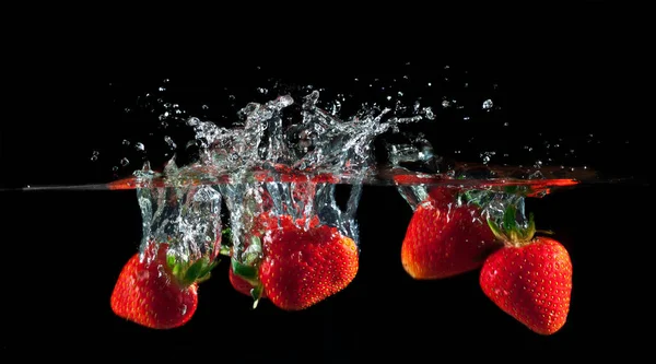 Strawberries splashing into water — Stock Photo, Image