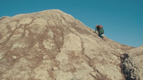 Young woman climbing the hill in the desert and raises her hands up — Stock Video