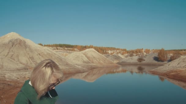 Junge Frau in einer menschenleeren Landschaft, die mit ihrem Smartphone in der Hand im Internet surft — Stockvideo