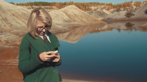 Junge Frau in einer menschenleeren Landschaft, die mit ihrem Smartphone in der Hand im Internet surft — Stockvideo