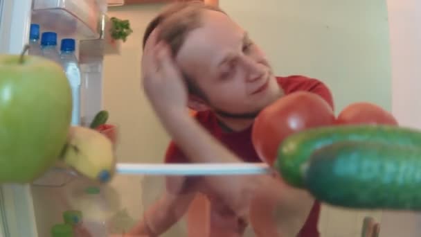 Young man opens the fridge takes bottle of water and drinks — Stock Video