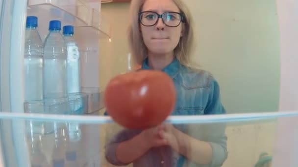 Jeune femme ouvre le réfrigérateur veulent manger, mais trouve une seule tomate et desparately prend et mange — Video