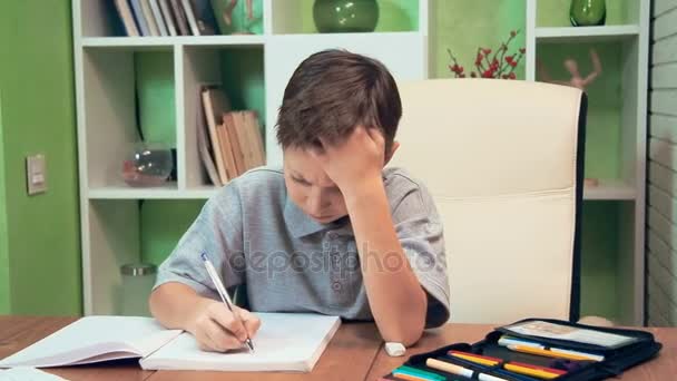 Маленький мальчик делает домашнее задание дома — стоковое видео