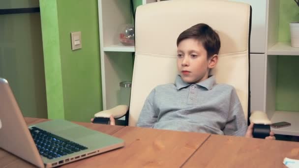 Грустный мальчик, смотрящий фильм на ноутбуке — стоковое видео
