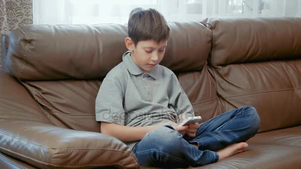 Мальчик пишет смс по телефону — стоковое видео