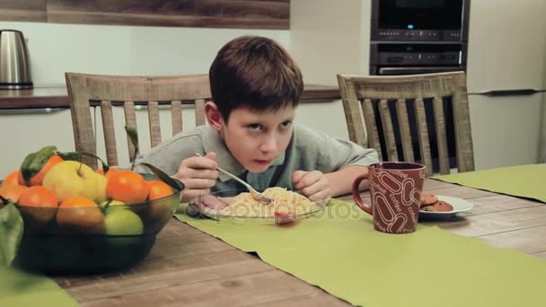 Хлопчик їсть макарони на кухні — стокове відео