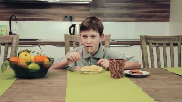 Хлопчик їсть макарони на кухні — стокове відео