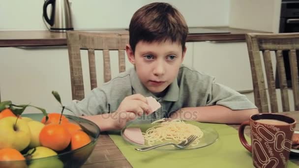 Menino comendo massa na cozinha — Vídeo de Stock