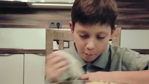 Мальчик ест макароны на кухне — стоковое видео
