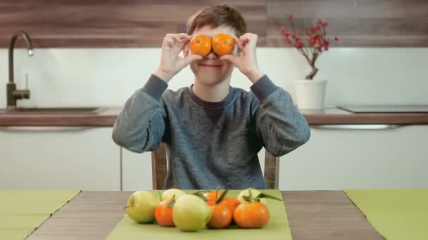 Funny little boy holding mandarins in front of his eyes and having fun — Stock Video