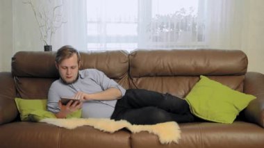 Genç adam kanepede döşenmesi ve internette sörf