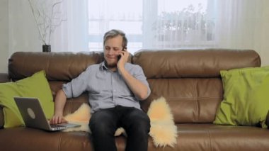 Kanepede oturan ve telefonda konuşurken genç adam