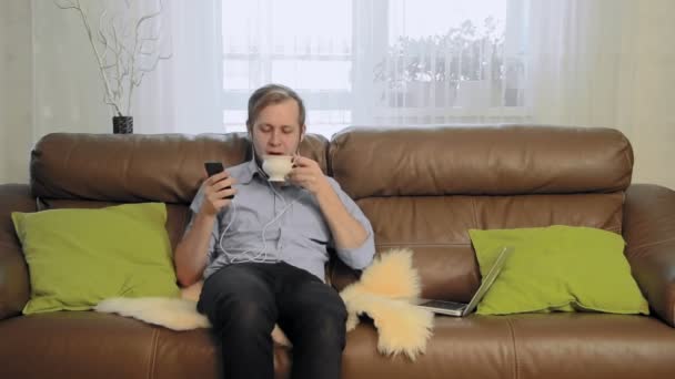 Mladý muž pití čaje, poslouchá hudbu a zpěv — Stock video